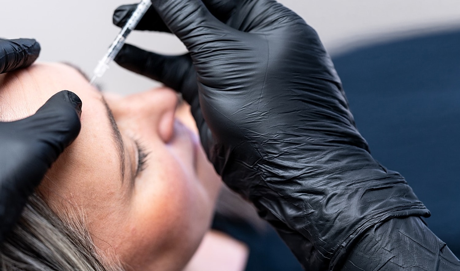 Administering aesthetic treatment with syringe and gloves